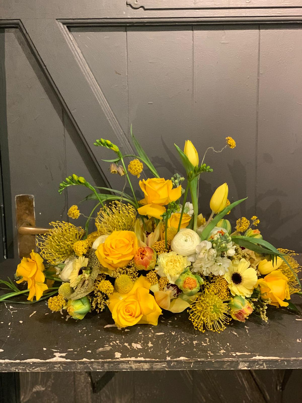 Lang gul dekoration med roser og tulipaner på et bord