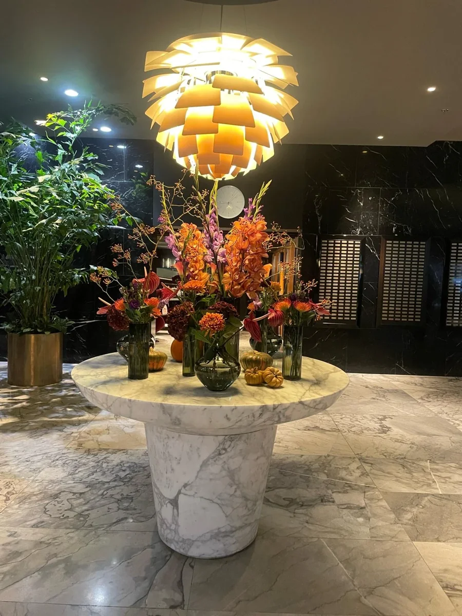 Høje arrangementer med orange og lyserøde blomster på et marmorbord