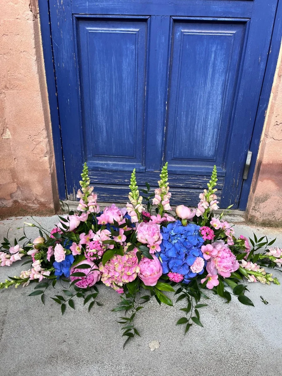 Lav dekoration med lyserøde roser og blå hortensia foran en blå dør