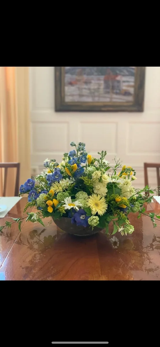 Borddekoration med gule roser og blå blomster i en skål